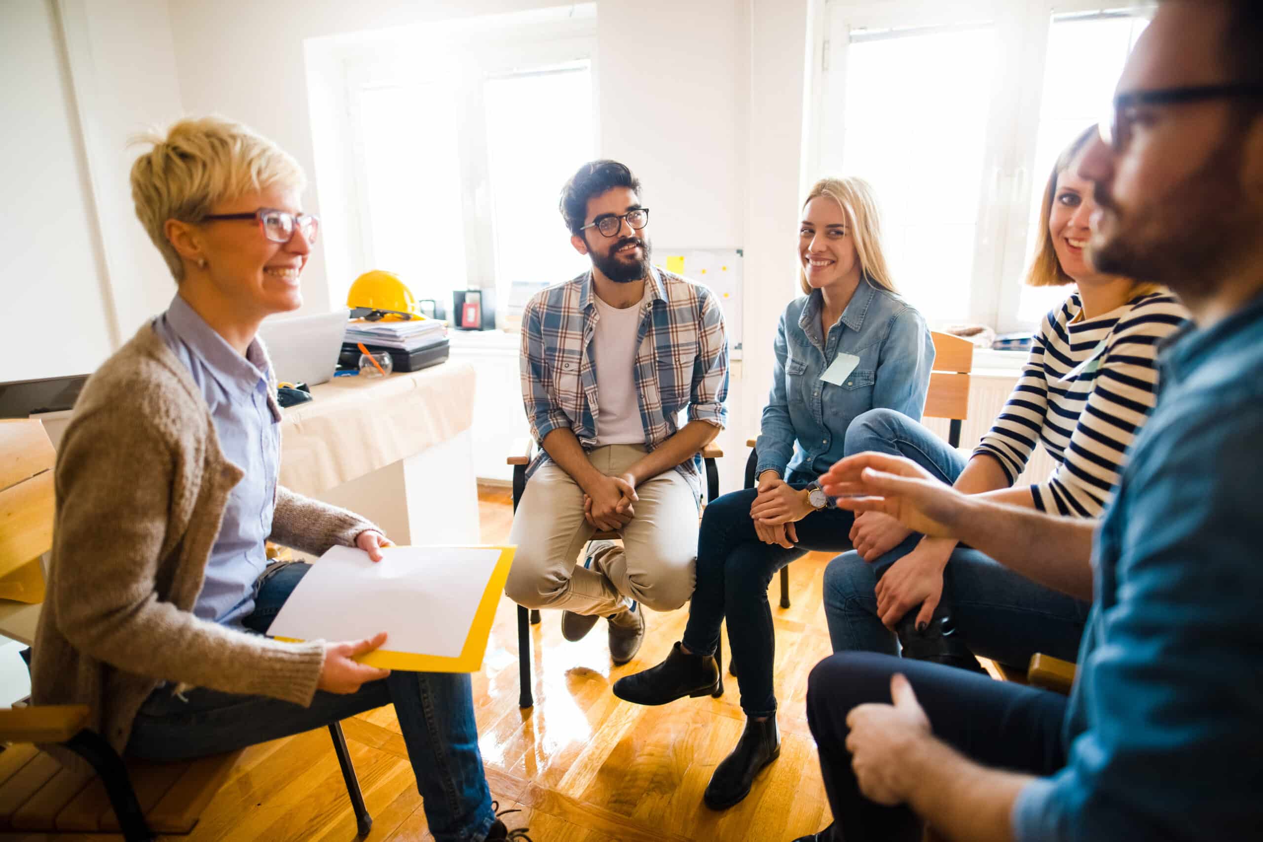Group of people sitting in a circle on group therapy. Looking at their therapist and listening ti her story. Group of people sitting in a circle on group therapy. Looking at their therapist and listening ti her story.