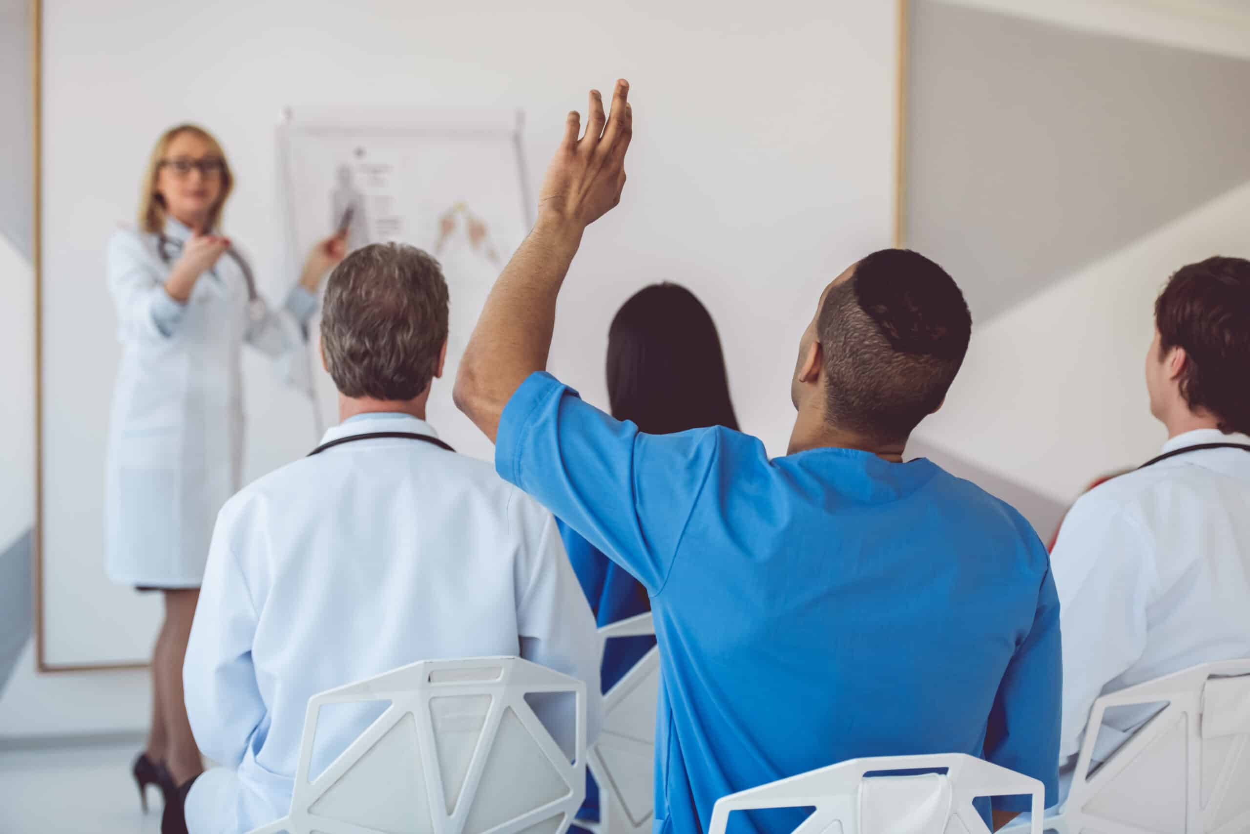 Medical doctors at the conference Beautiful medical doctor is giving lecture for her colleagues using a whiteboard and schemes